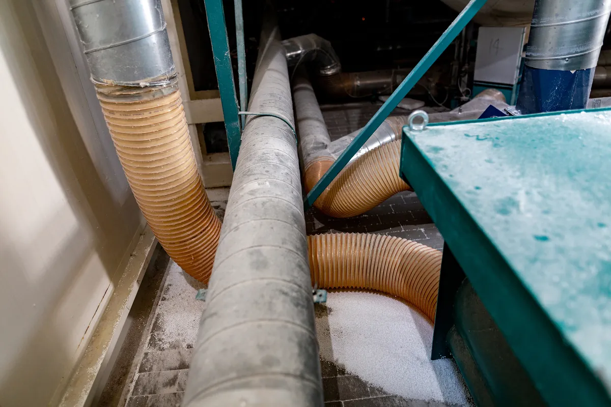 Industrial metal and ribbed ductwork in a Los Angeles facility covered in white construction debris, requiring professional post-construction cleaning by SoCal Green Air and Chimney.