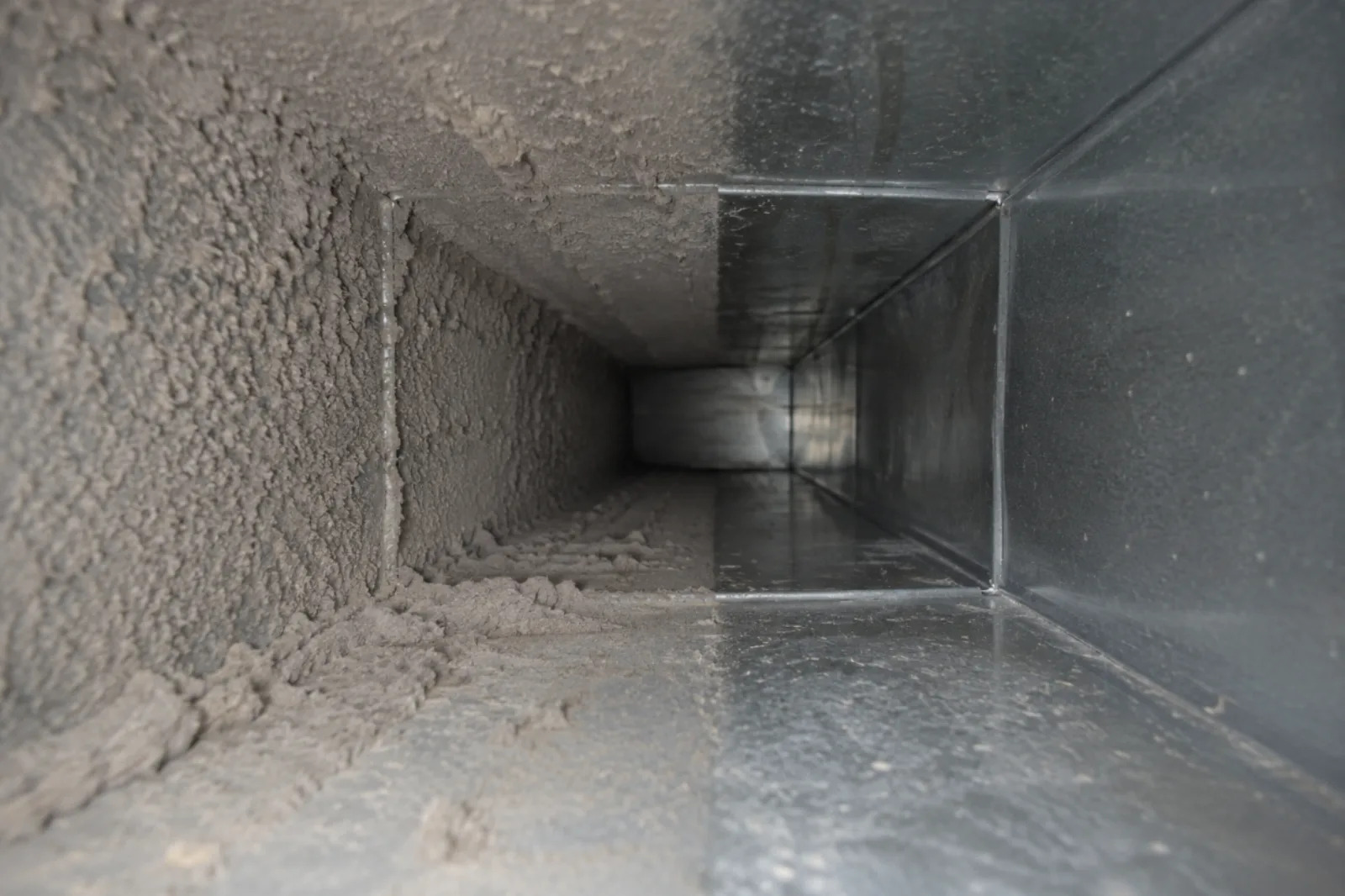 Dust buildup inside residential AC air ducts restricting airflow and reducing cooling efficiency.