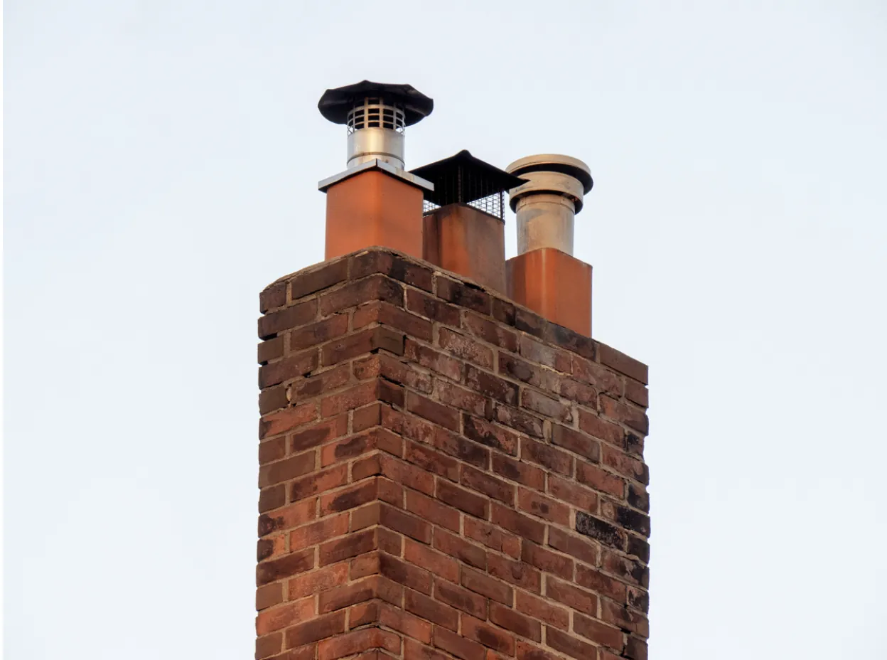 Detailed view of a traditional red brick chimney and textured roof tiles during a professional annual maintenance inspection in Los Angeles.