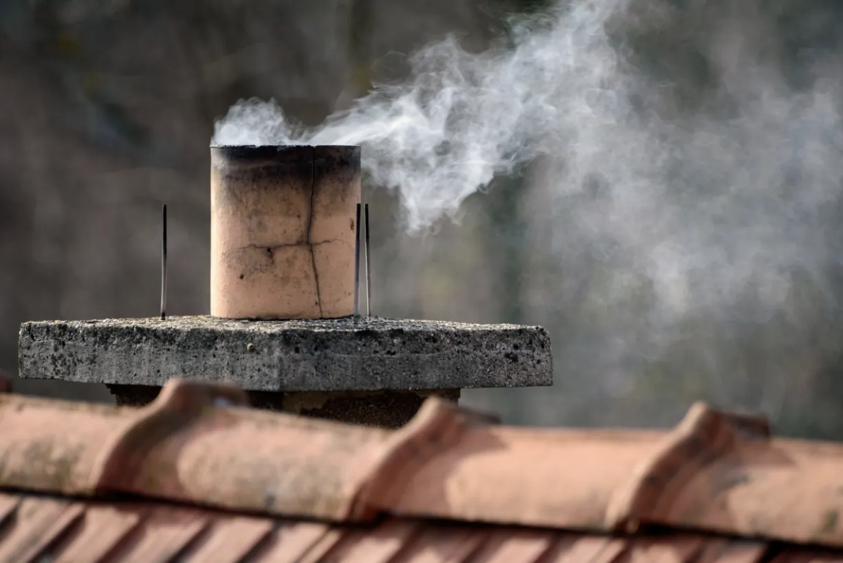 Damaged beige chimney flue with visible cracks on a red tiled roof in Los Angeles, illustrating the need for professional flue cleaning and masonry repair to ensure home heating safety.