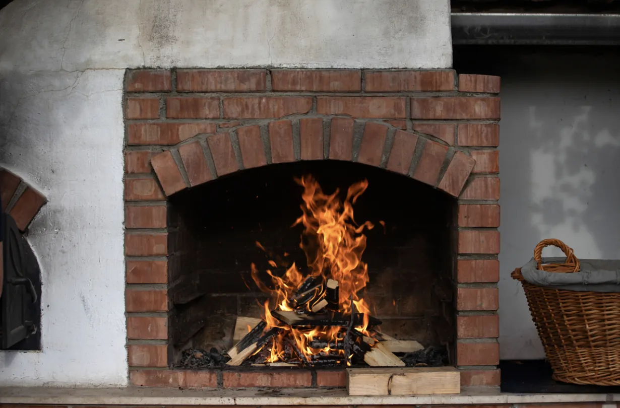 A vibrant roaring fire in a red brick fireplace in a Los Angeles home, demonstrating proper draft and airflow following a professional chimney cleaning and safety inspection.