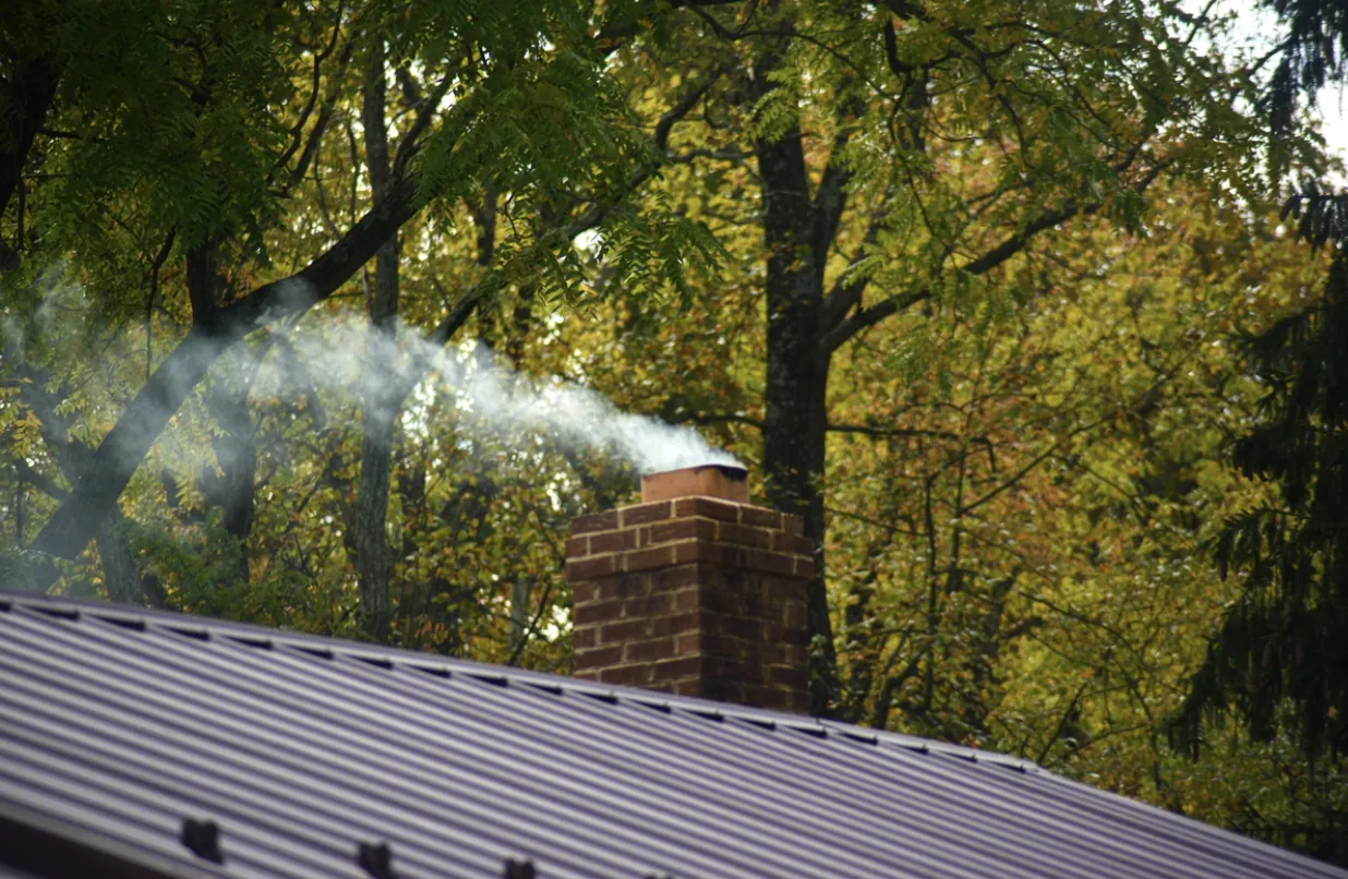 Active reddish-brown brick chimney releasing smoke, illustrating the need for professional flue cleaning and creosote removal for homes in the San Fernando Valley.