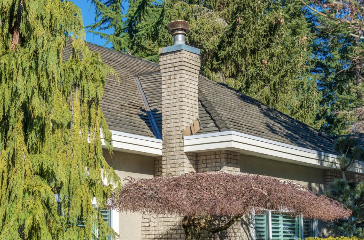 Exterior view of a suburban Los Angeles home featuring a brick chimney with a metal cap and tile roof, highlighting the importance of annual creosote removal for residential safety.