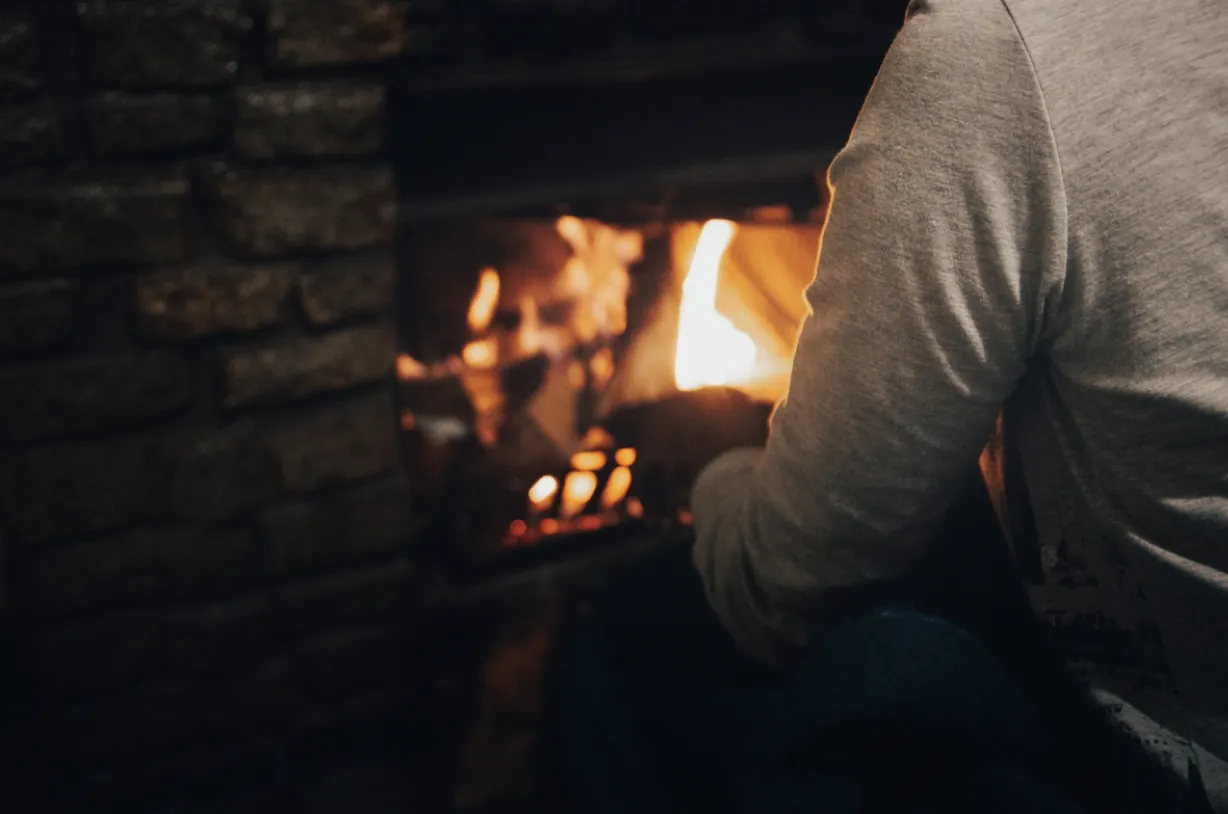 A homeowner enjoying a warm, clean stone fireplace in a Los Angeles residence, highlighting the comfort and safety provided by professional chimney and hearth cleaning services.