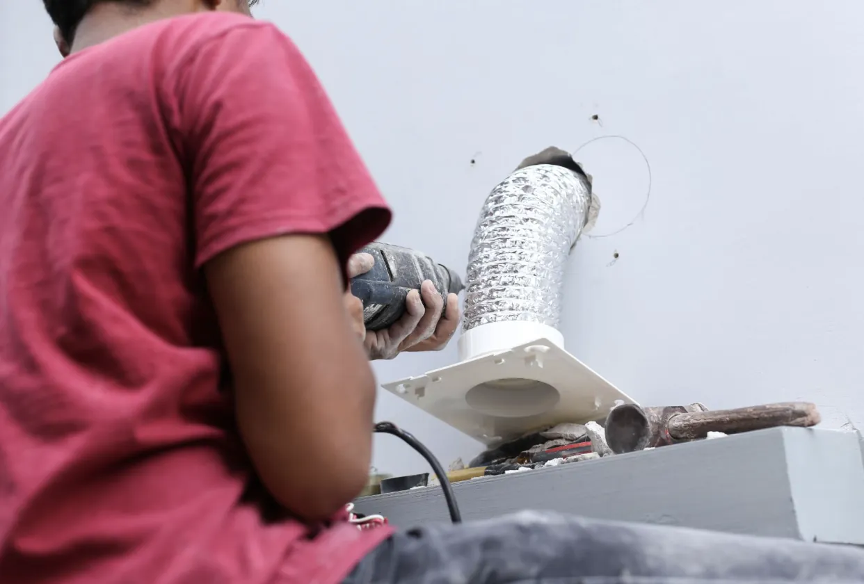 A technician installing a new ventilation duct for a clothes dryer to ensure proper airflow and safety in a Los Angeles residence.
