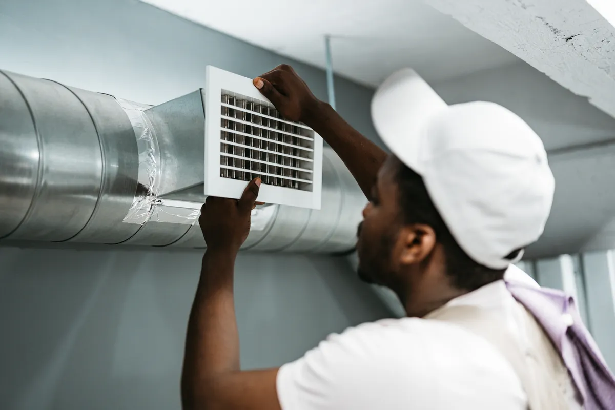 A technician adjusting and sealing a dryer vent connection to a metal duct to ensure airtight airflow for a home in Los Angeles.